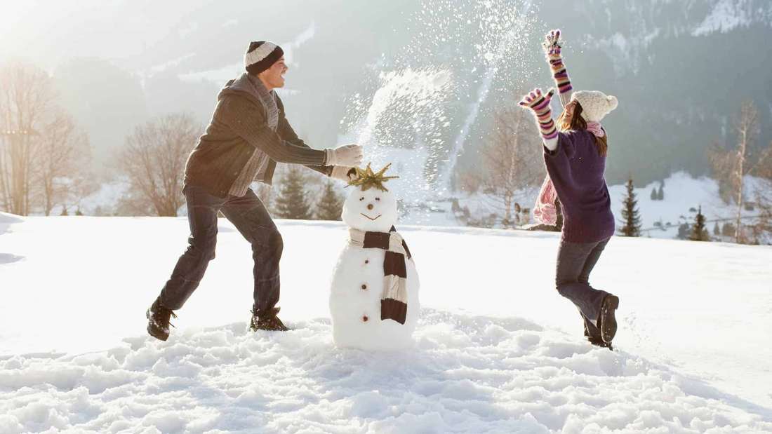 Зимние выходные парень и девушка делают снеговика