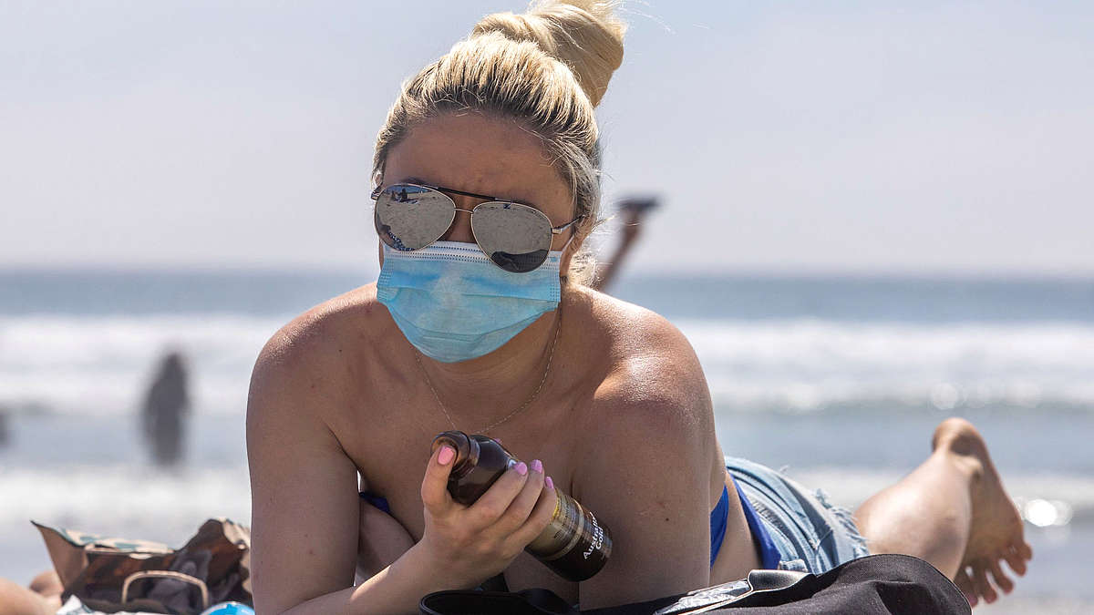 отдыхающие на пляже в медицинской маске